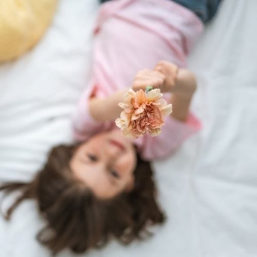 bambina che tiene in mano un garofano per la festa della mamma