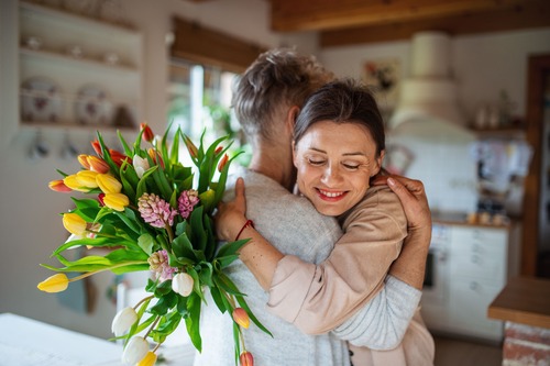 due persone che si abbracciano e in primo piano un mazzo di fiori