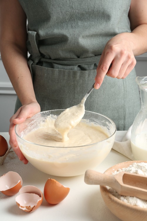 Preparazione della torta mimosa impasto montato in ciotola con uova e ingredienti sul piano di lavoro